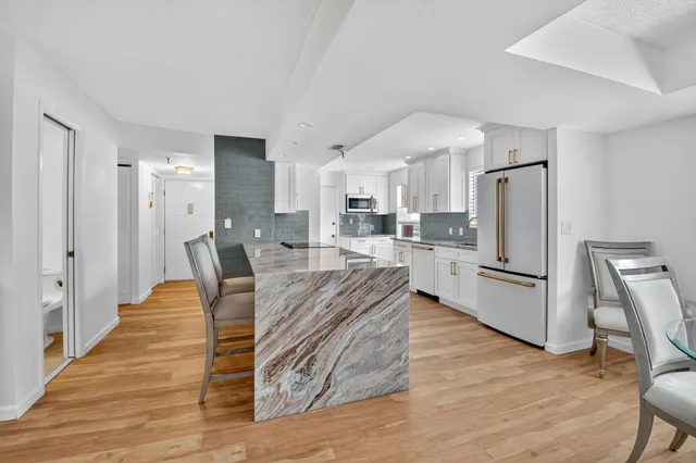 a large kitchen with a table chairs refrigerator and wooden floor