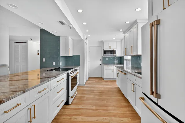 a large kitchen with stainless steel appliances double vanity sink and a large window