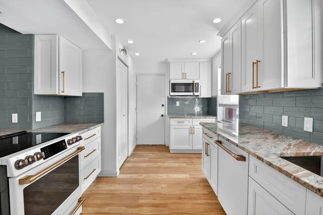 a kitchen with kitchen island granite countertop a sink a stove and refrigerator