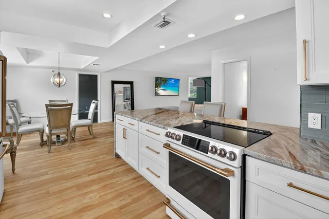 a large white kitchen with sink stove and chairs