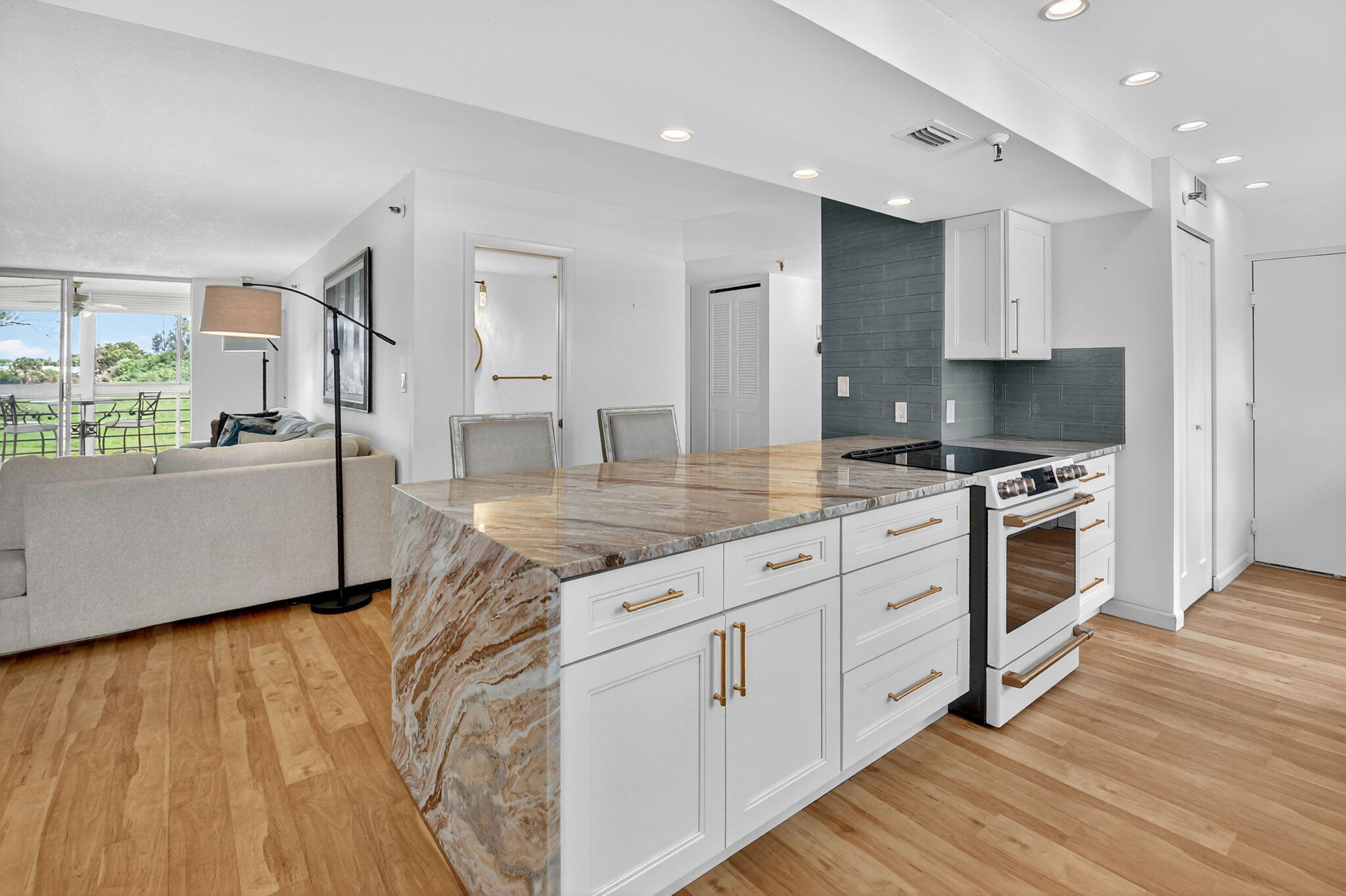 5340 Northwest 2nd Avenue, Unit 220 Boca Raton, FL 33487 - Photo 4 of 46 a kitchen with kitchen island granite countertop a stove a sink and white cabinets with wooden floor