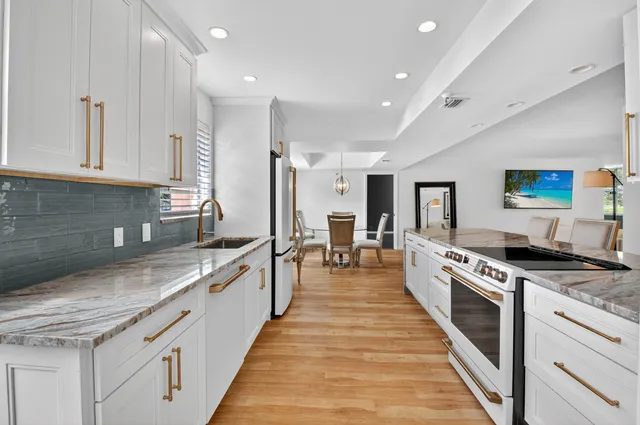 a large kitchen with stainless steel appliances granite countertop a stove top oven a sink a dining table and chairs