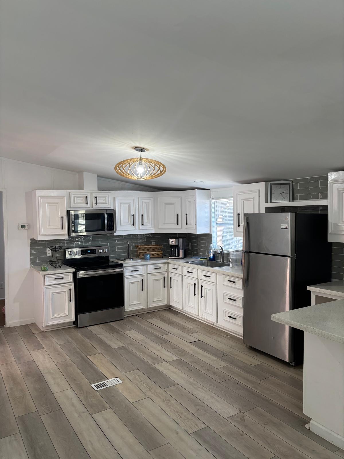1109 Hurst Creek Road Austin, TX 78734 - Photo 4 of 18 Kitchen with stainless steel appliances, decorative backsplash, white cabinets, and light wood-style floors