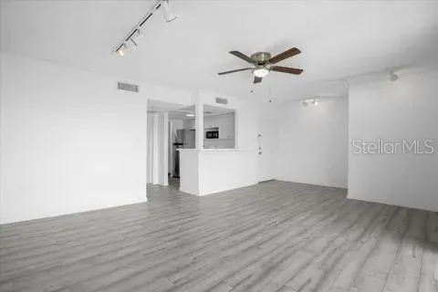 a view of empty room with wooden floor and ceiling fan