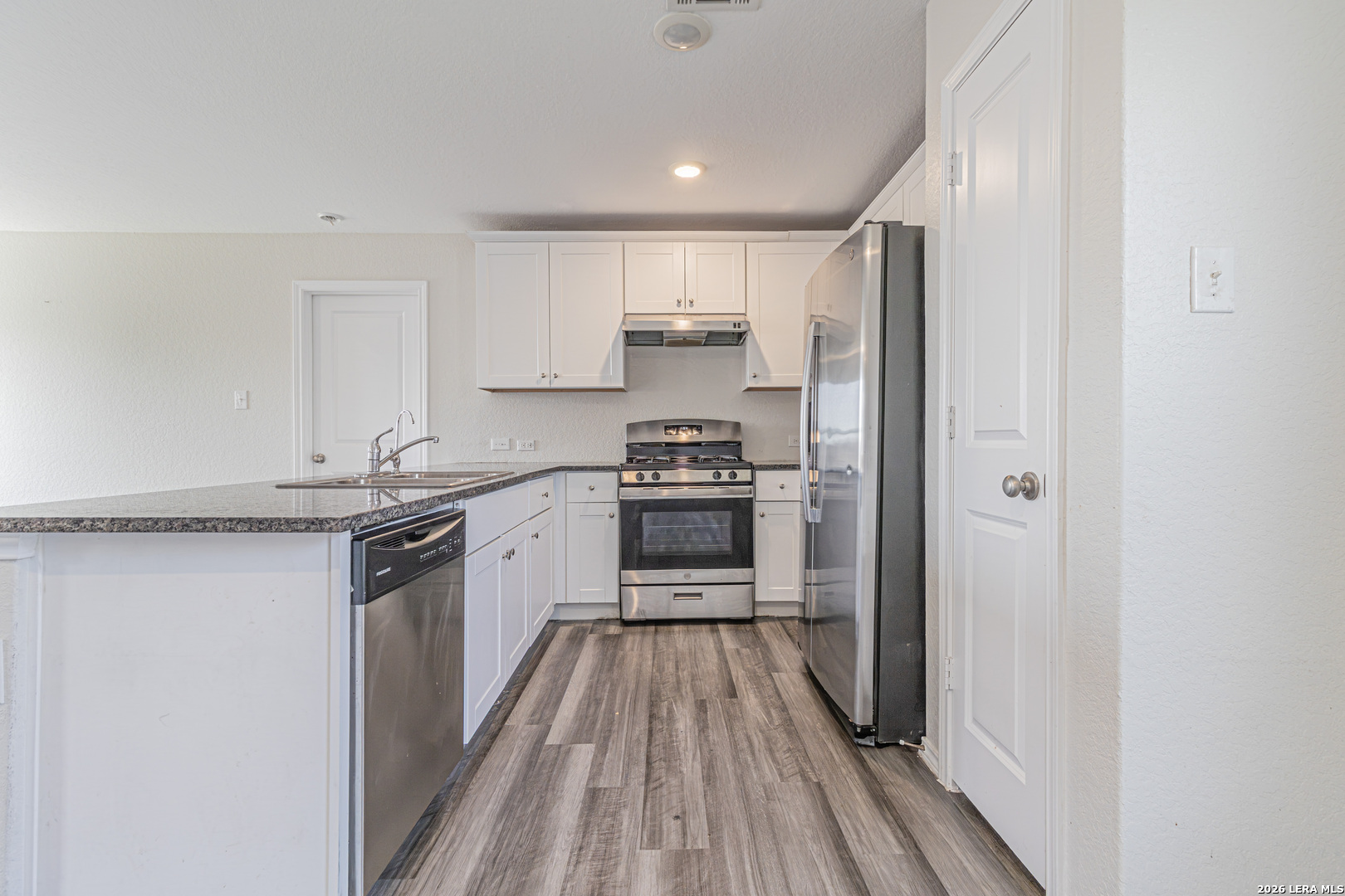 3814 Pickles Way Converse, TX 78109 - Photo 12 of 27 a kitchen with granite countertop a refrigerator oven a sink and white cabinets