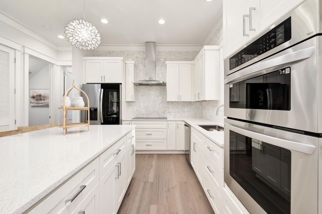 a kitchen with granite countertop white cabinets and stainless steel appliances