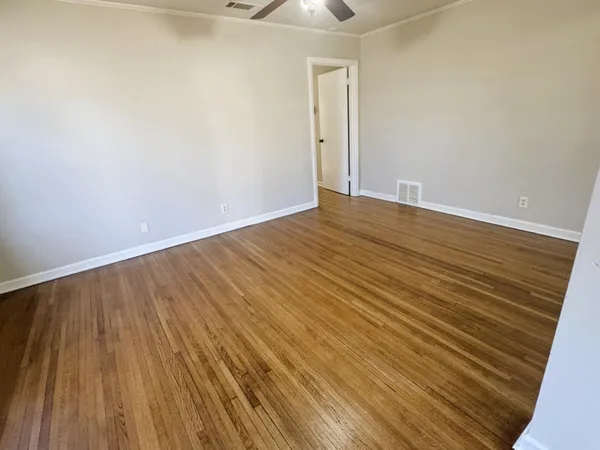 a view of an empty room with wooden floor and a window