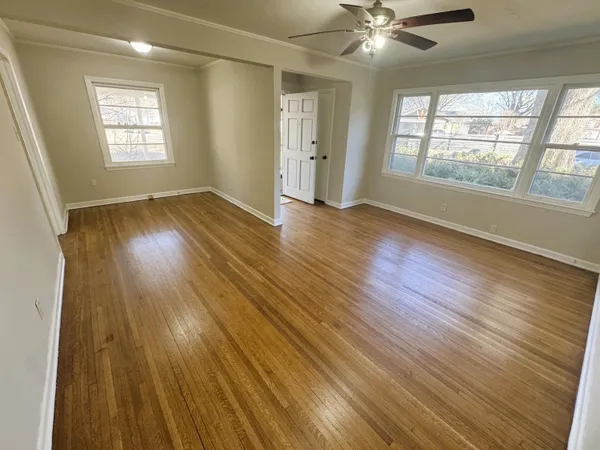a view of an empty room with wooden floor and a window
