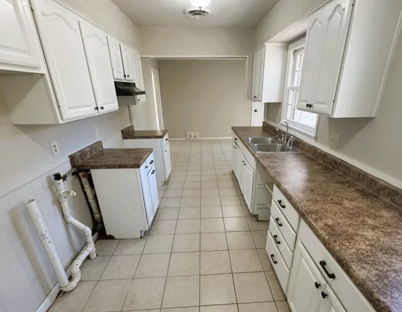 a kitchen with granite countertop a sink a stove top oven and cabinets