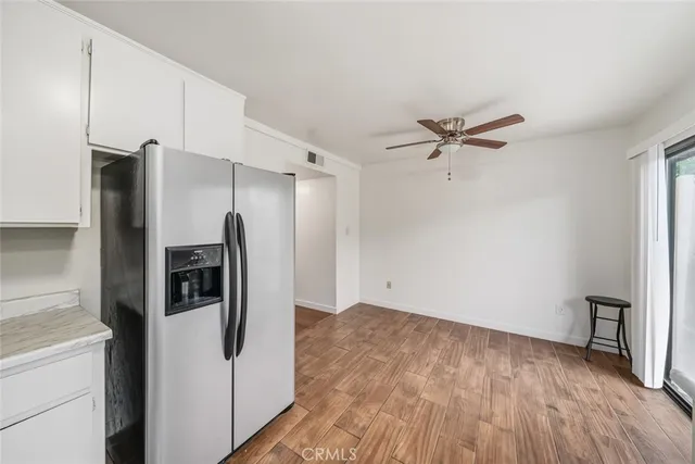 a kitchen with stainless steel appliances a refrigerator a sink a stove and white cabinets with wooden floor