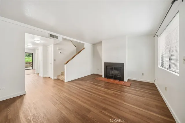 a view of empty room with wooden floor and fireplace