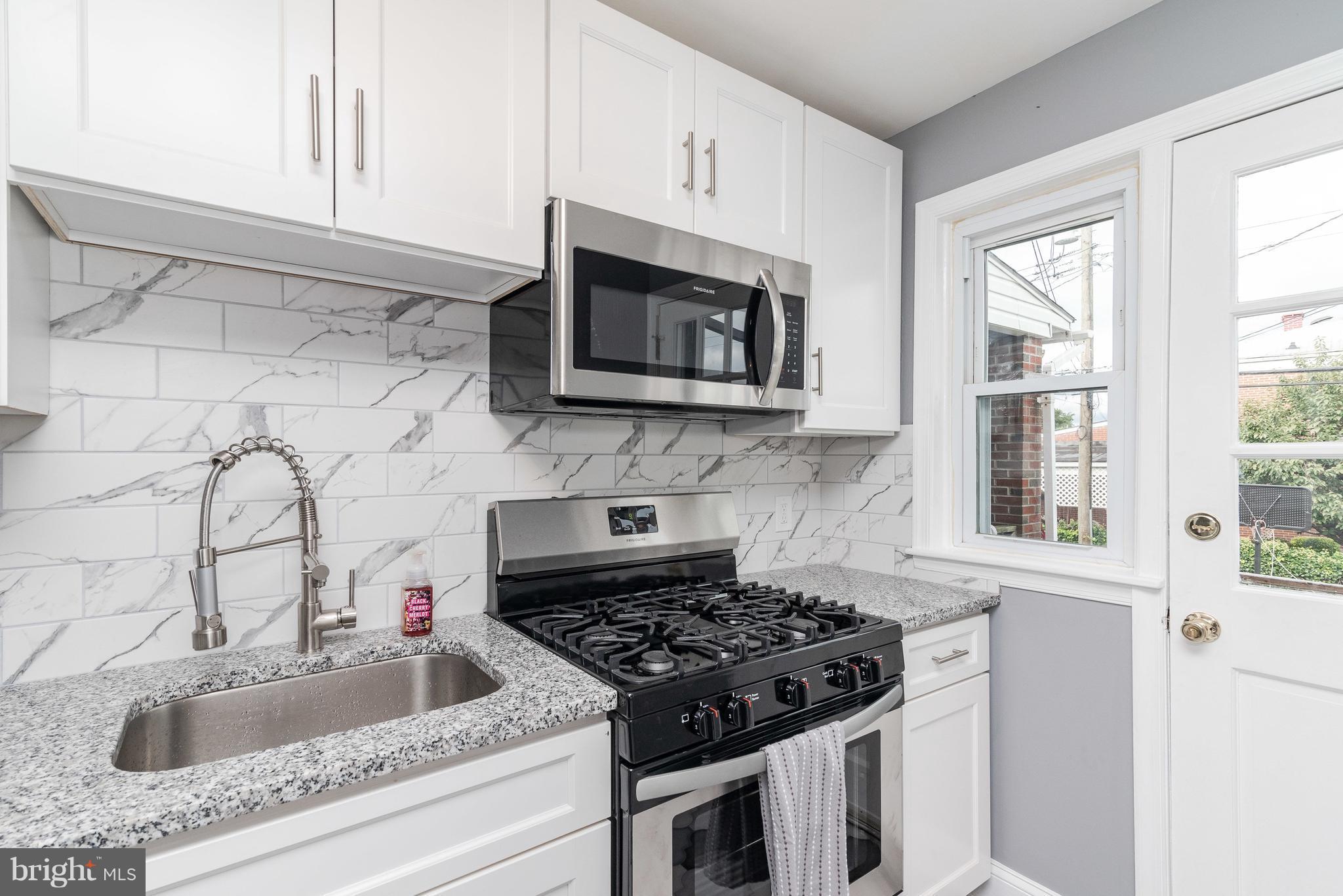 700 Aldworth Road Baltimore, MD 21222 - Photo 13 of 30 a kitchen with granite countertop a sink stove and microwave