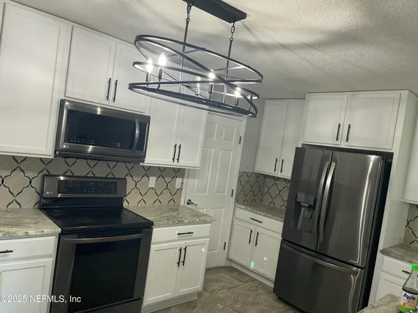 a kitchen with stainless steel appliances granite countertop a refrigerator a stove top oven a sink and dishwasher