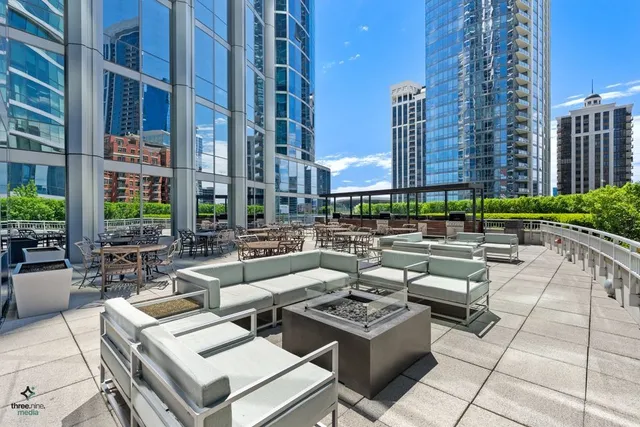 a view of a patio with couches and a fire pit and potted plants