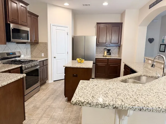 a kitchen with kitchen island granite countertop a sink stove and refrigerator