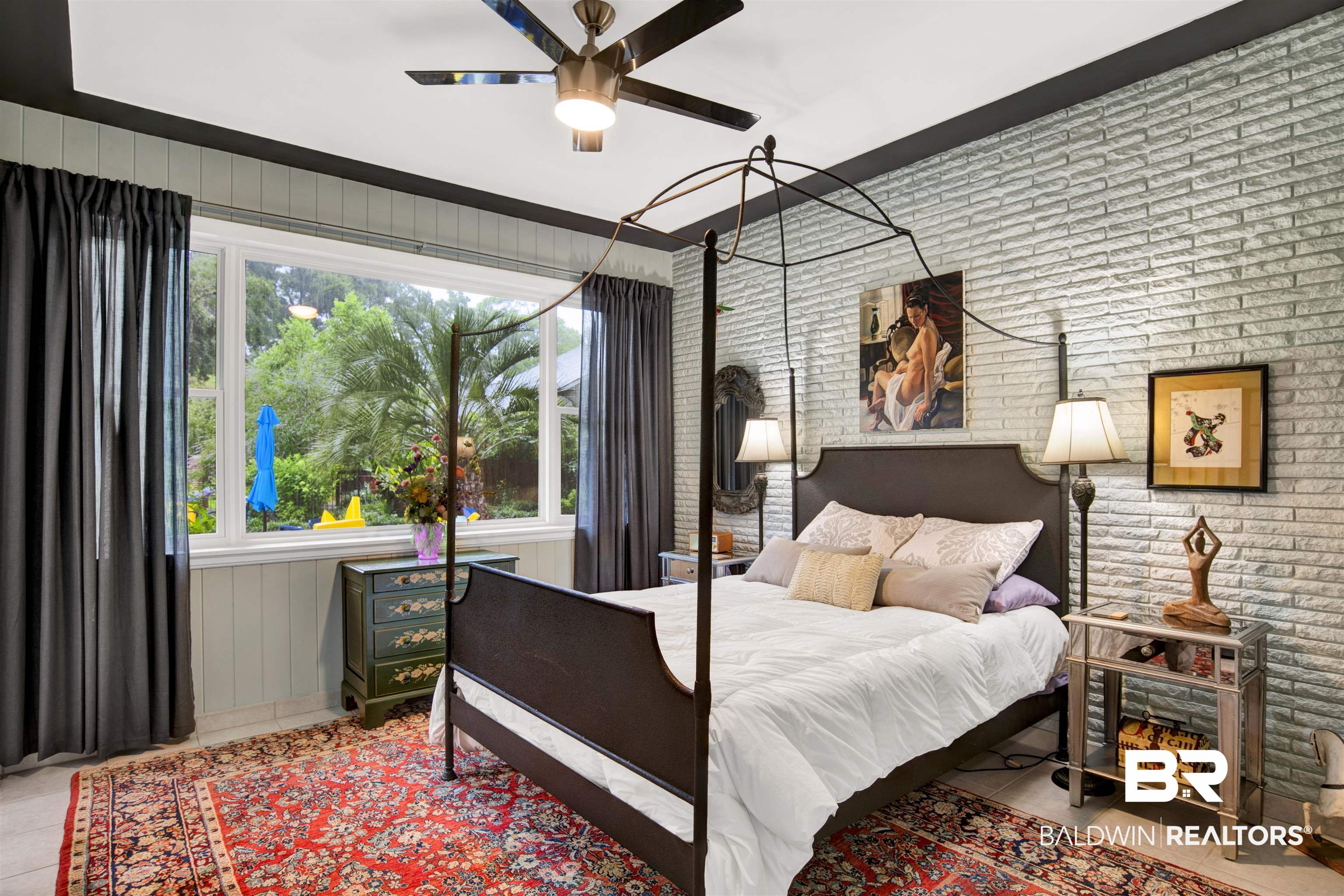 809 Bernard Circle Mobile, AL 36693 - Photo 20 of 75 Bedroom featuring an exposed brick accent wall, a wide picture window, paneling along the lower wall, a ceiling fan with integrated lighting, and a dark trim ceiling