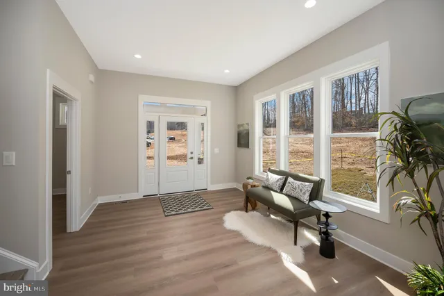 a living room with furniture floor to ceiling windows and wooden floor