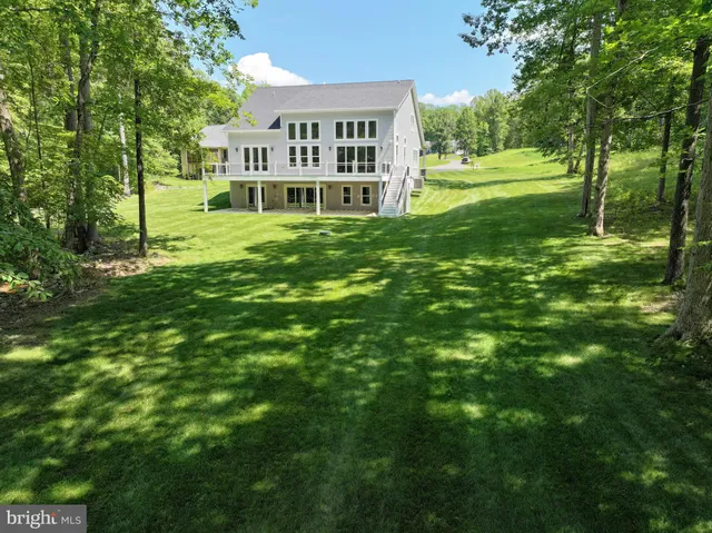 a view of a house with a big yard and large trees