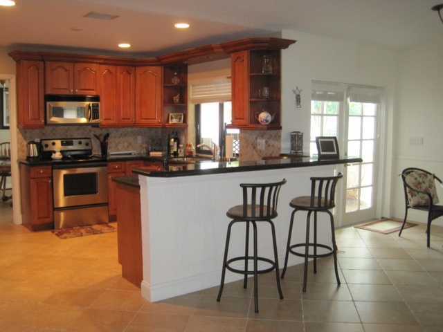 5038 Marina Circle Boca Raton, FL 33486 - Photo 5 of 19 a kitchen with stainless steel appliances granite countertop a stove top oven a sink a dining table and chairs