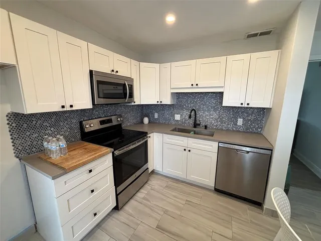 a kitchen with stainless steel appliances granite countertop a stove a sink and a refrigerator