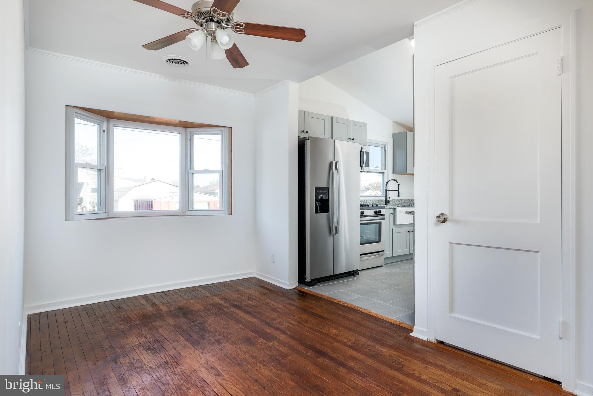 3005 Sollers Point Road Baltimore, MD 21222 - Photo 11 of 33 a view of a kitchen with a refrigerator a ceiling fan and wooden floor