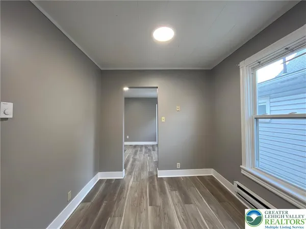 a view of an empty room with wooden floor and a window