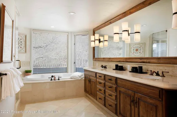 a bathroom with a tub a sink and a large mirror
