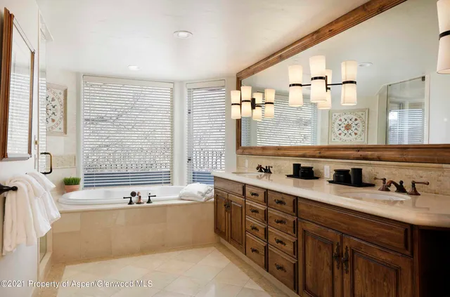 a bathroom with a tub a sink and a large mirror