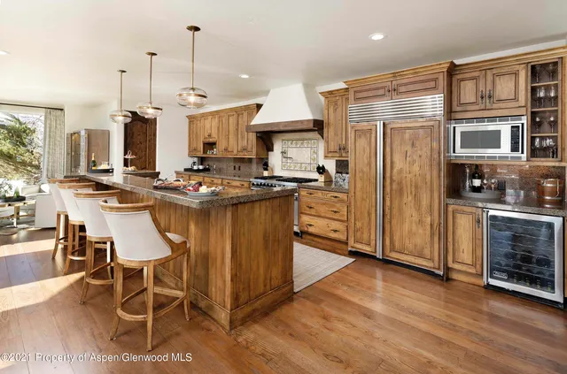 a kitchen with stainless steel appliances granite countertop a stove top oven a sink dishwasher a dining table and chairs with wooden floor