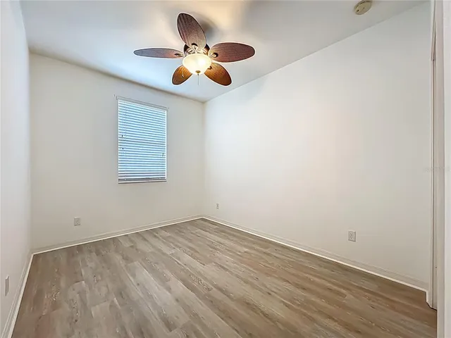 an empty room with wooden floor and chandelier fan
