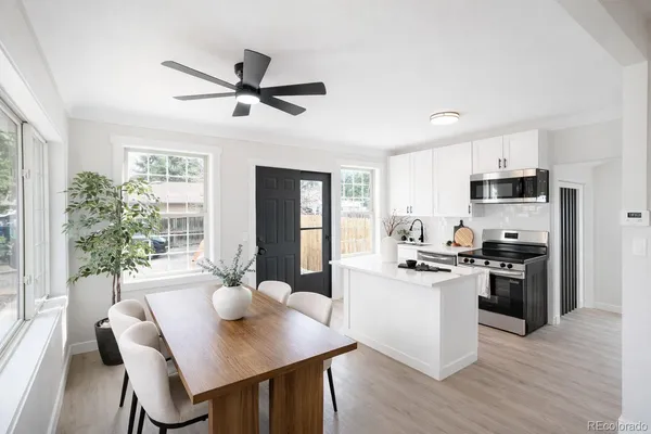 a kitchen with stainless steel appliances granite countertop a stove a refrigerator a dining table and chairs with wooden floor