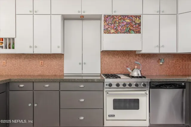 a kitchen with stainless steel appliances granite countertop a stove and a white cabinets
