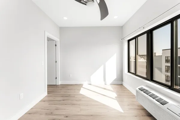 a view of an empty room with wooden floor and a window
