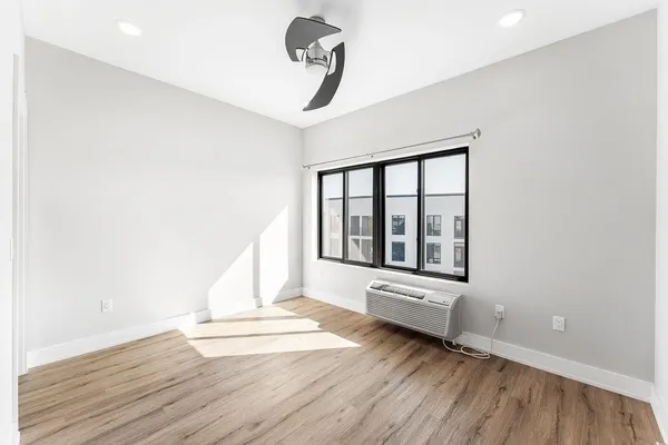 a view of empty room with wooden floor and fan