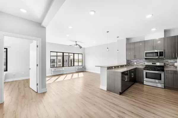 a large kitchen with granite countertop a stove top oven a sink dishwasher a refrigerator and a dining table with wooden floor