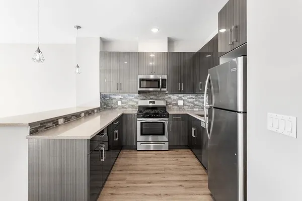 a kitchen with stainless steel appliances granite countertop a refrigerator a stove a sink and a microwave