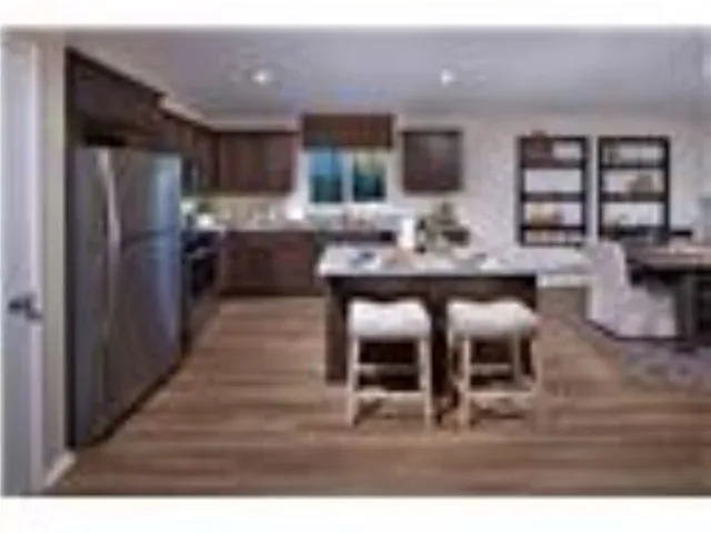 a kitchen with stainless steel appliances kitchen island granite countertop a refrigerator and cabinets