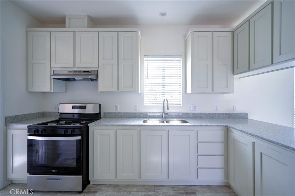 13369 Centola Road Phelan, CA 92371 - Photo 11 of 34 a kitchen with stainless steel appliances granite countertop a sink a stove and cabinets