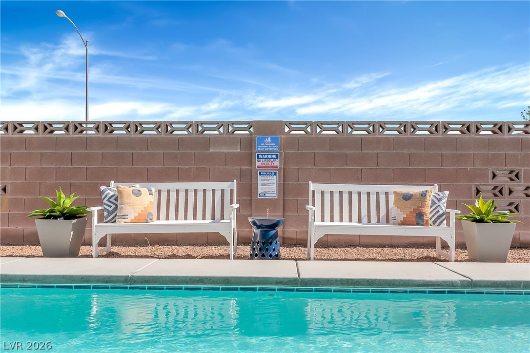 101 Beaver Ridge Avenue North Las Vegas, NV 89031 - Photo 36 of 42 A tranquil backyard oasis features a glistening pool, complemented by seating and lush plantings against a textured privacy wall.