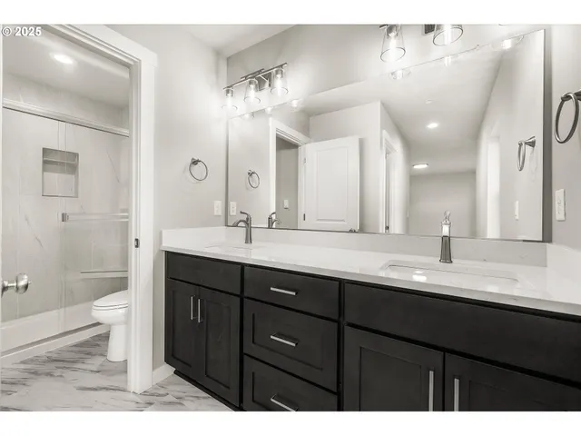 a bathroom with a granite countertop sink a toilet a large mirror and shower
