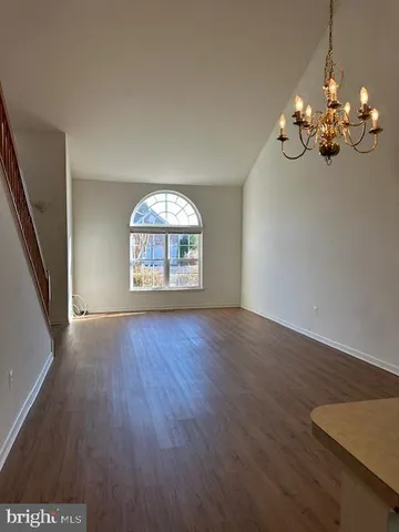 an empty room with wooden floor chandelier and windows