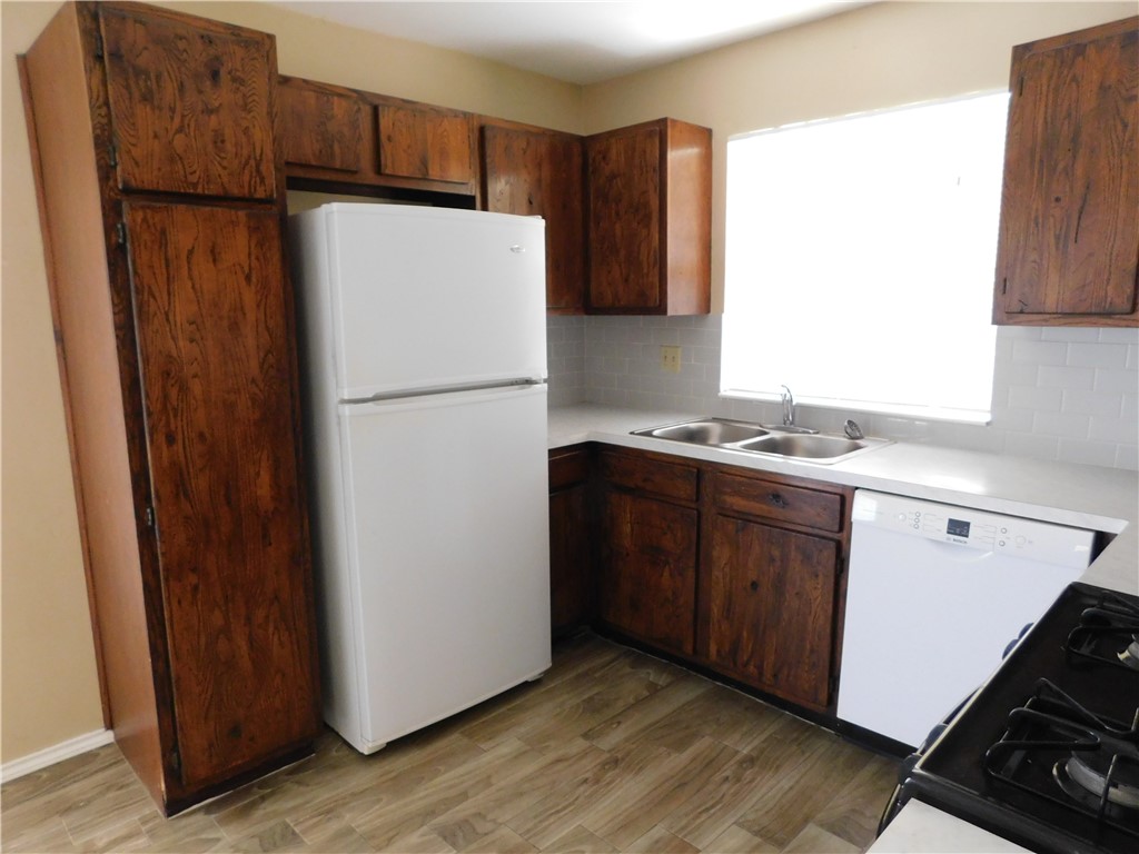 1900 Prairie Knoll Court, Unit A Austin, TX 78758 - Photo 7 of 18 a white refrigerator freezer sitting inside of a kitchen with stainless steel appliances wooden floor