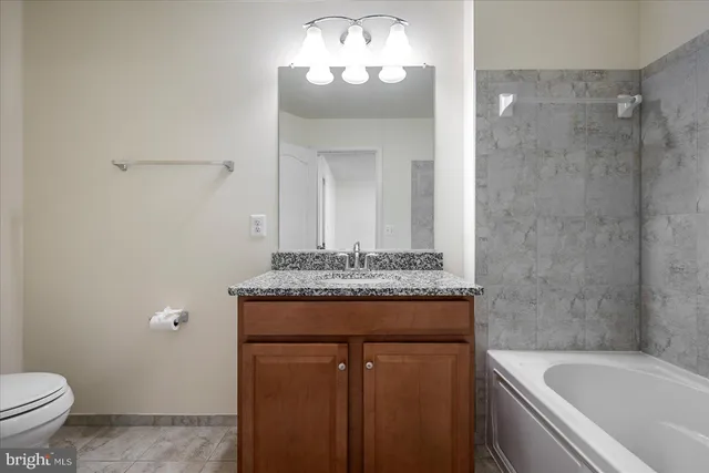 a bathroom with a granite countertop sink a toilet and a bathtub