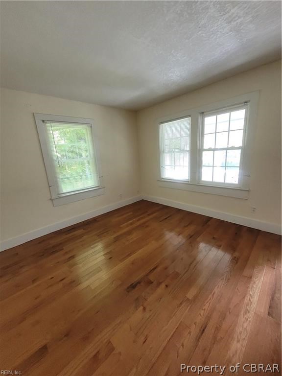 863 Urbanna Road Saluda, VA 23149 - Photo 3 of 24 Spare room featuring hardwood / wood-style floors and a textured ceiling