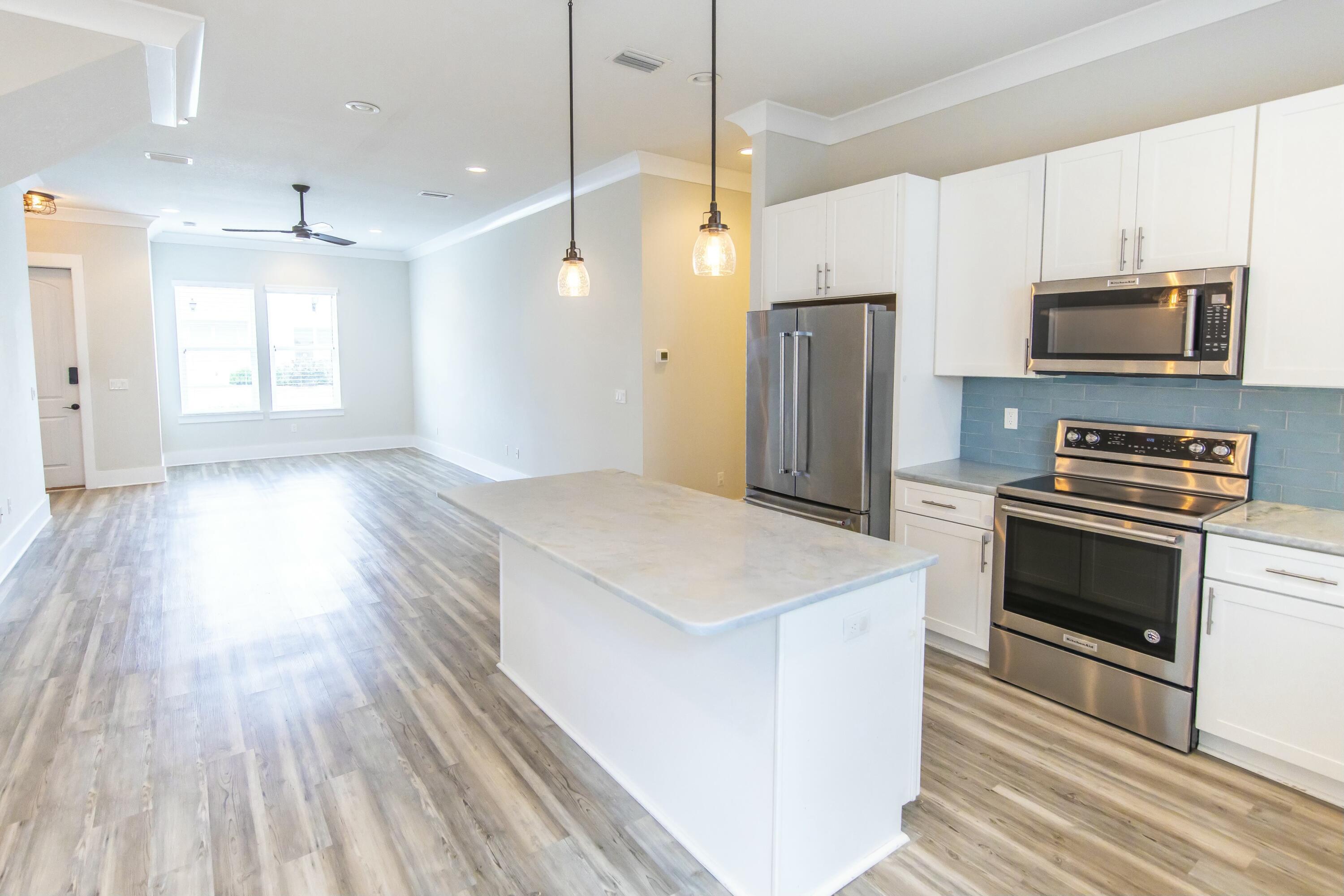 995 Airport Road, Unit 37 Destin, FL 32541 - Photo 5 of 46 a kitchen with kitchen island wooden floors appliances and cabinets