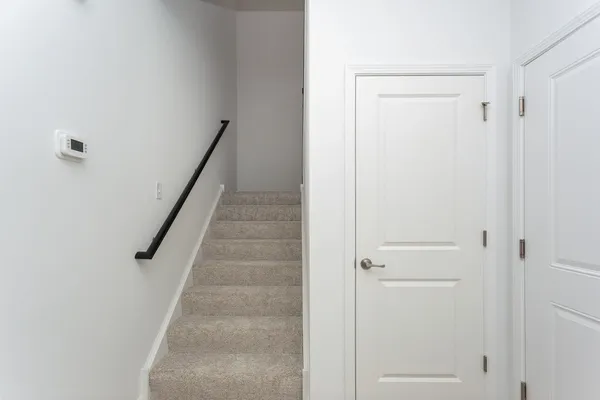 a view of staircase with white walls and white door