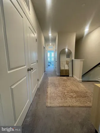 a view of a hallway to a room with wooden floor and staircase