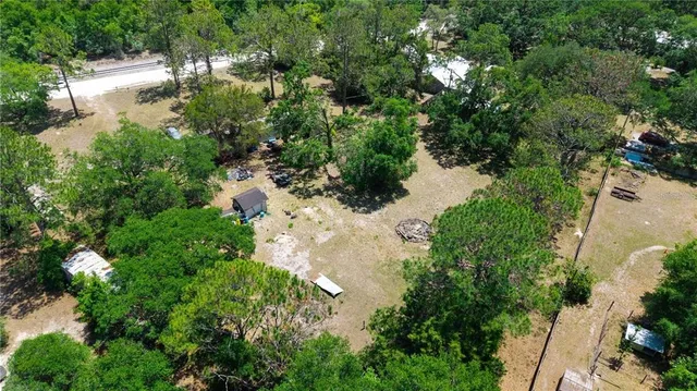 an aerial view of residential house with outdoor space and trees all around