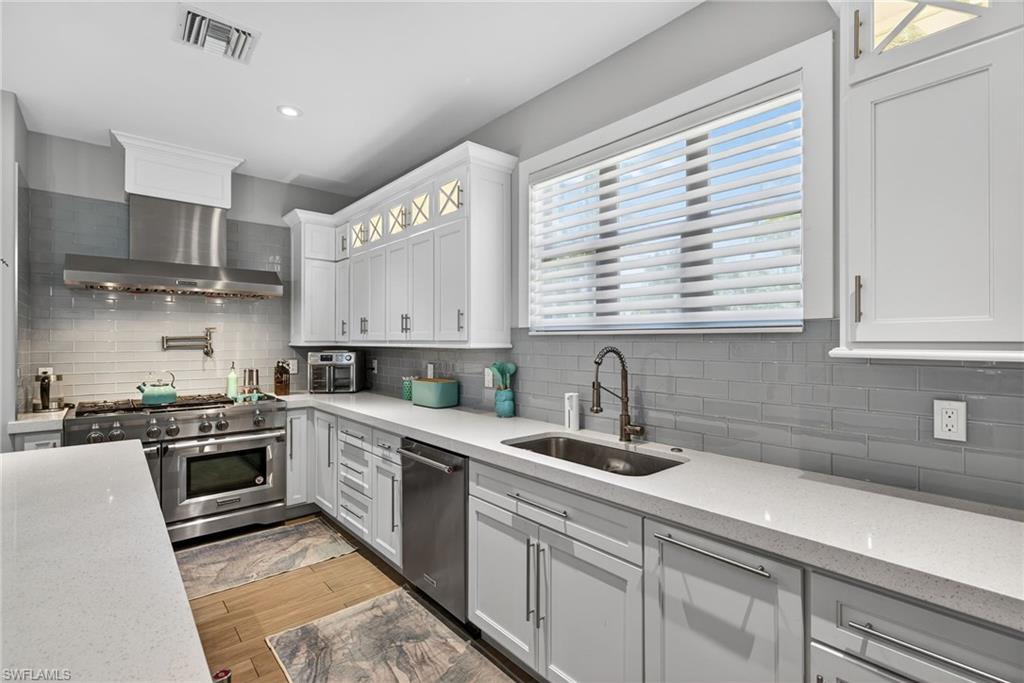 5577 Lancewood Way Naples, FL 34116 - Photo 11 of 44 a kitchen with a sink a stove and cabinets