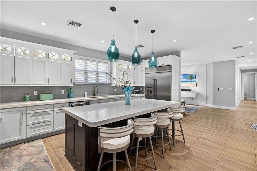5577 Lancewood Way Naples, FL 34116 - Photo 10 of 44 a kitchen with stainless steel appliances kitchen island granite countertop a table chairs and a refrigerator